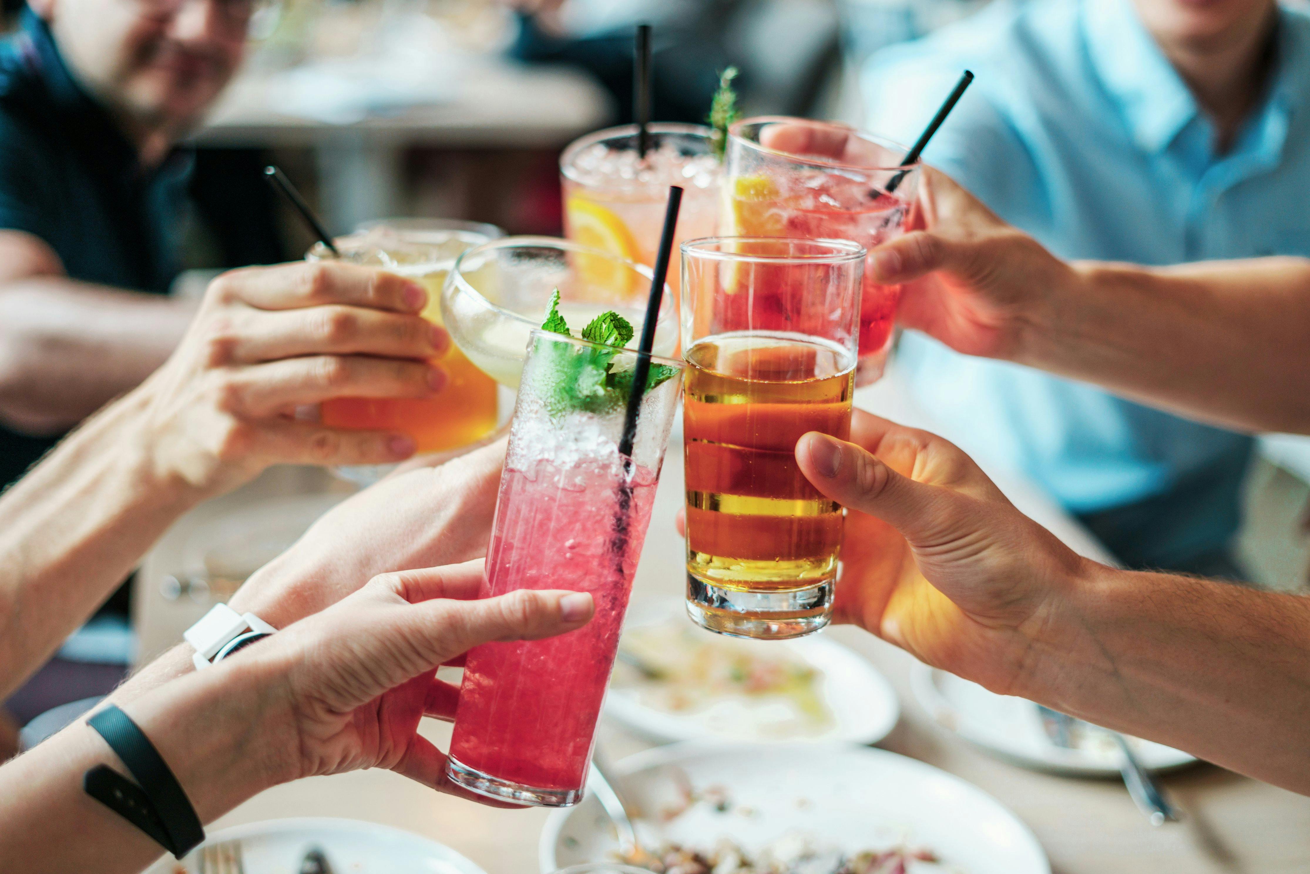 Freunde stoßen mit alkoholfreien und alkoholischen Getränken auf den Apfelsaft-Paragraph an.